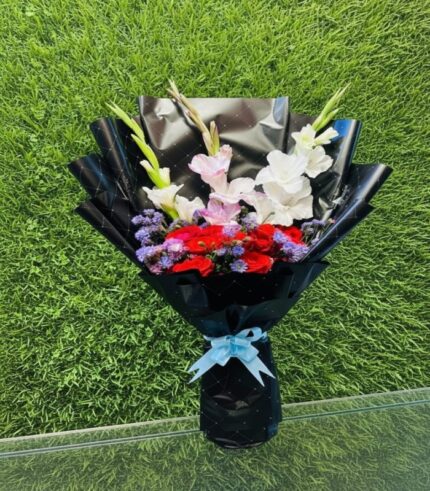 Gladiolus and red roses bouquet wrapped in black paper with blue ribbon
