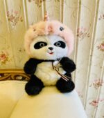 Cute unicorn panda teddy bear with pink hood sitting on sofa
